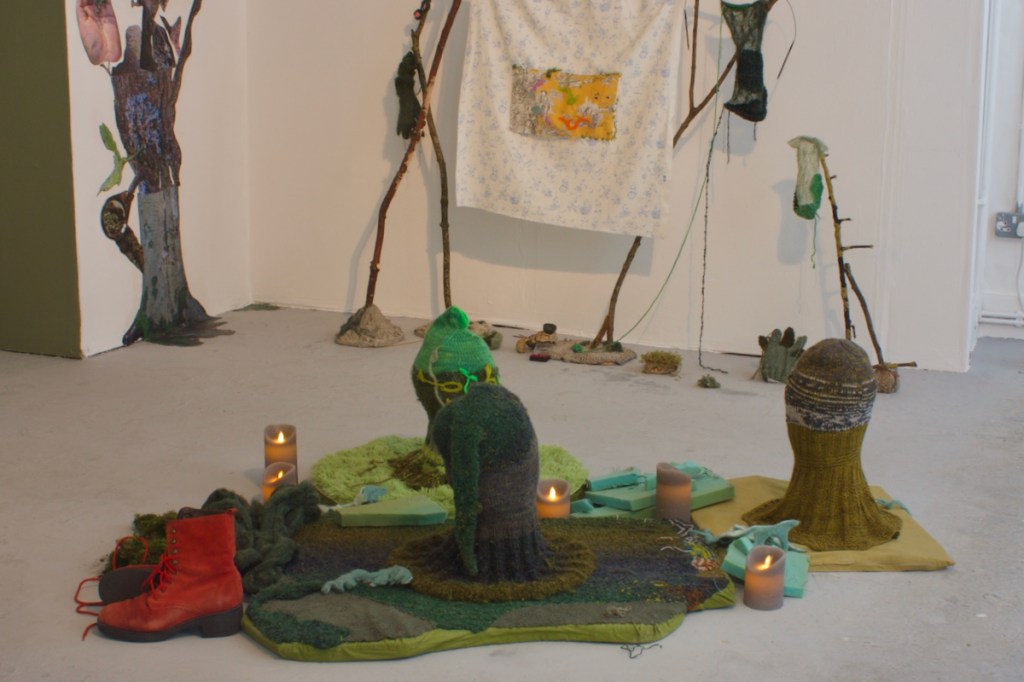 3 knitted heads and red boots with Chinoiserie hanging in background