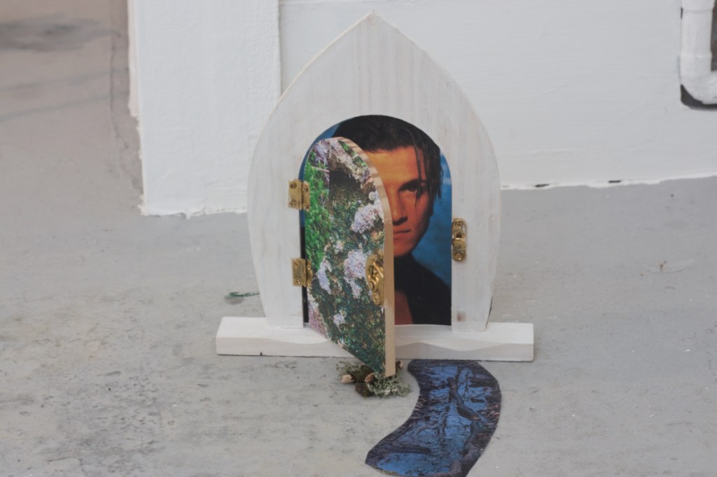 Peter Andre peering out from an arched mossy fairy door