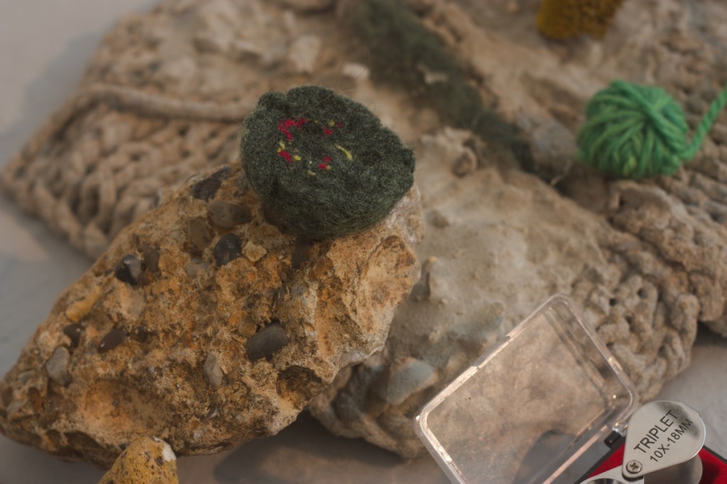 felted dark green wool ball half resting on concrete