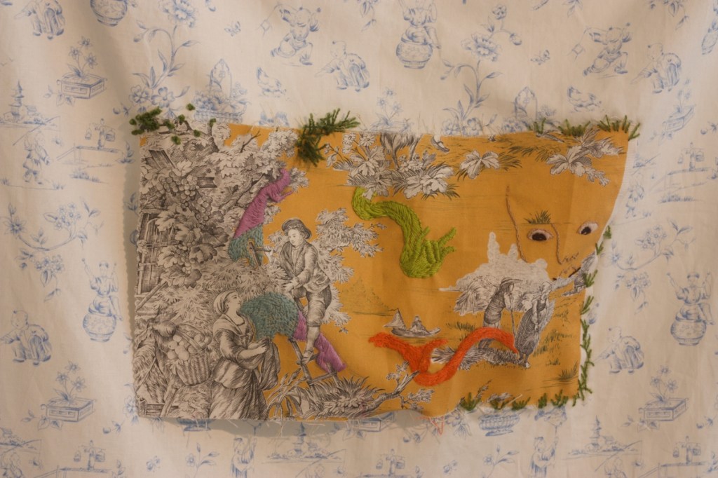 detail of hanging, showing embroidered toile panel against Chinoiserie background